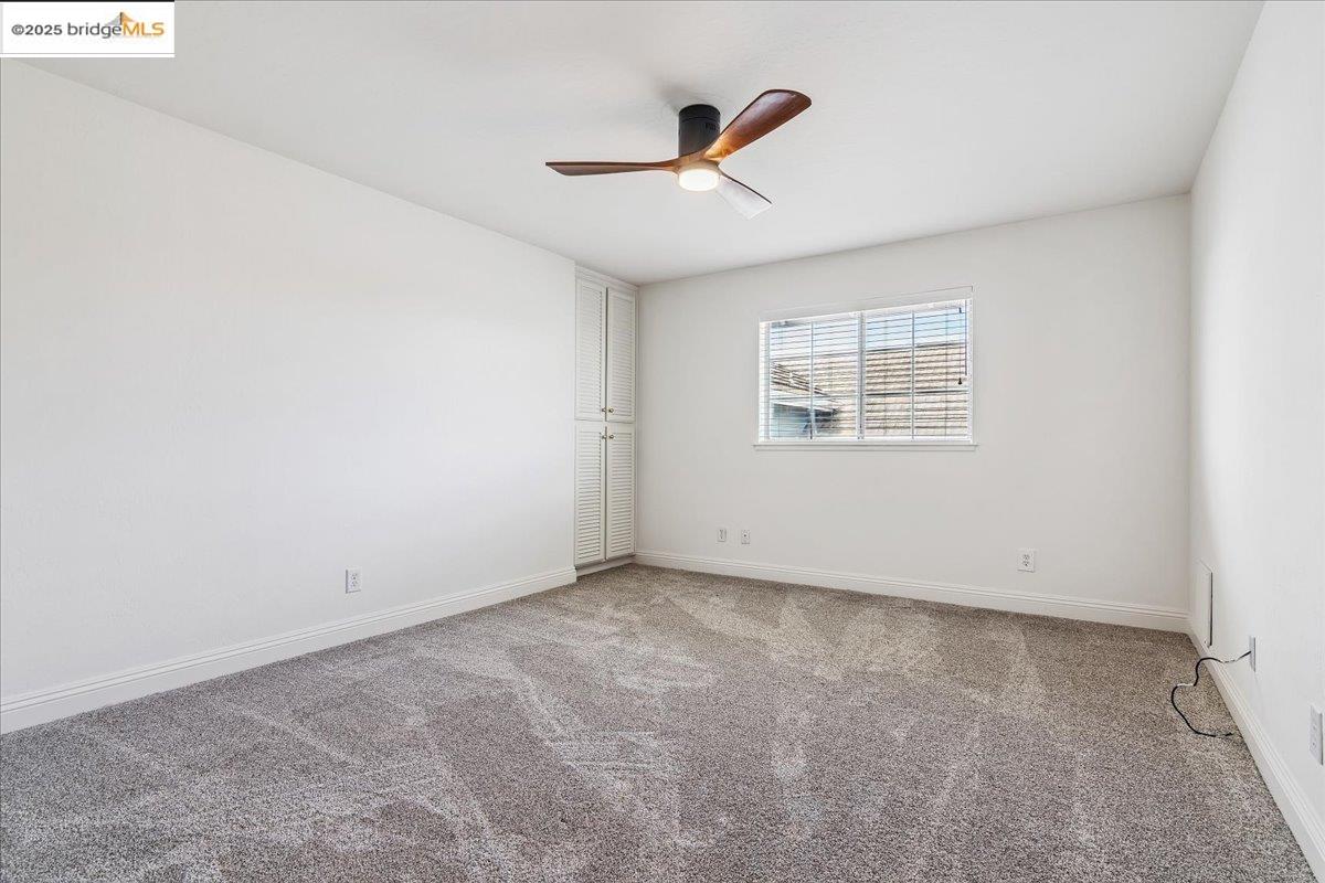 5752 Drakes Drive Discovery Bay, CA 94505 - Photo 22 of 32 an empty room with a ceiling fan and windows