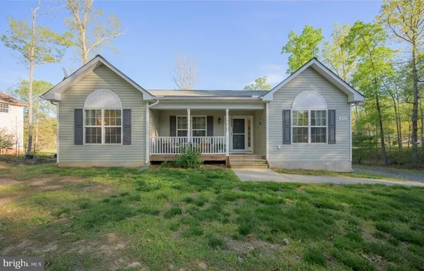 a front view of a house with a yard and trees
