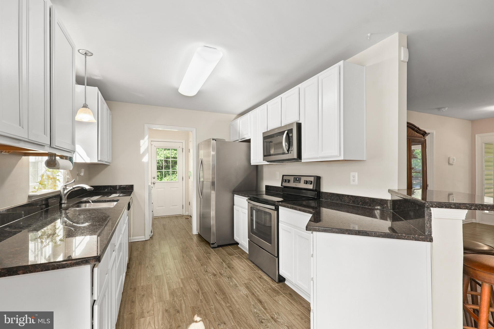 470 Jacoby Road Louisa, VA 23093 - Photo 7 of 16 a kitchen with granite countertop a stove a sink a refrigerator wooden floor and cabinets