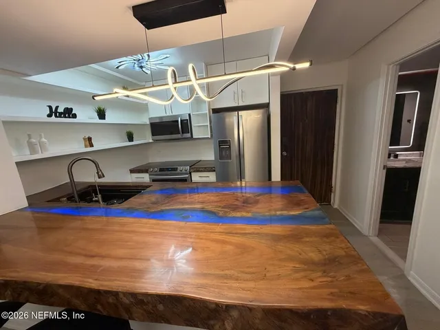 a room with stainless steel appliances wooden floor and chandelier
