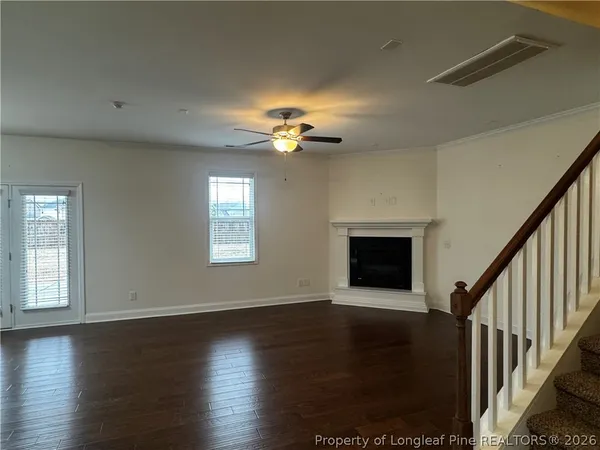 an empty room with wooden floor chandelier fan and windows