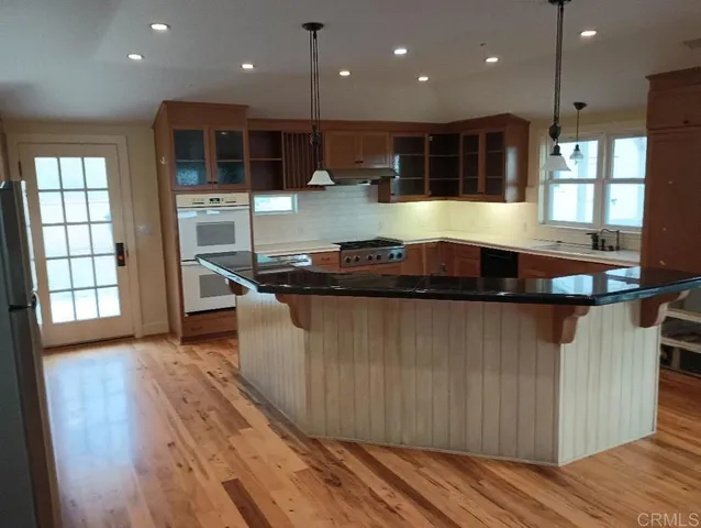 a kitchen with kitchen island granite countertop wooden floors and a sink