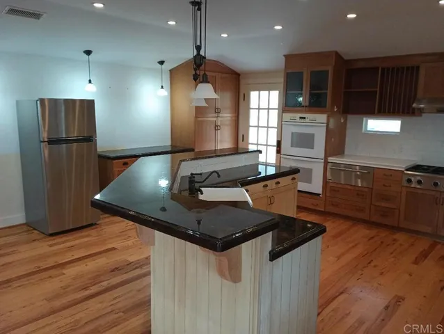 a kitchen with stainless steel appliances granite countertop a sink a stove and a refrigerator