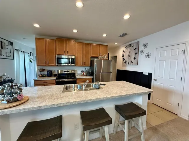 a kitchen with stainless steel appliances granite countertop a refrigerator a stove and a sink