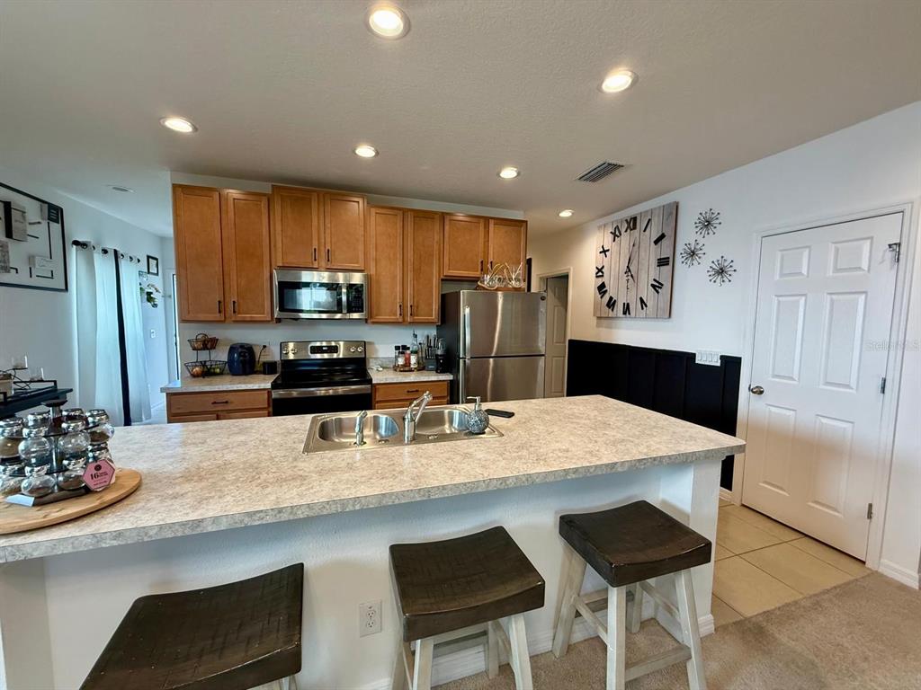 813 Marcel Loop Davenport, FL 33837 - Photo 6 of 34 a kitchen with kitchen island a refrigerator stove microwave and cabinets