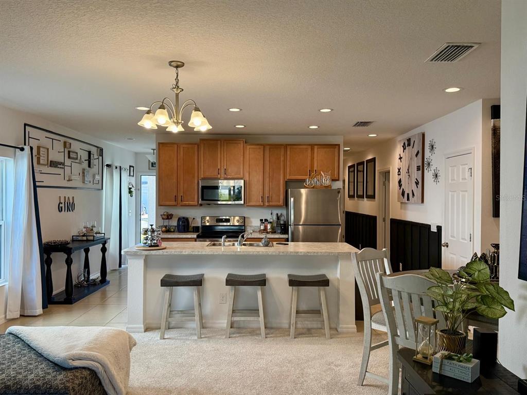 813 Marcel Loop Davenport, FL 33837 - Photo 10 of 34 a kitchen with stainless steel appliances kitchen island granite countertop a refrigerator and microwave