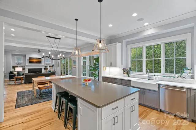 a open kitchen with stainless steel appliances granite countertop a stove top oven a sink and white cabinets with wooden floor