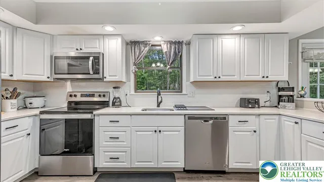 a kitchen with stainless steel appliances granite countertop a sink and cabinets with wooden floors