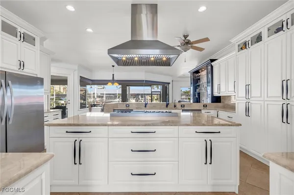 a kitchen with stainless steel appliances kitchen island granite countertop a refrigerator a sink dishwasher a dining table and chairs