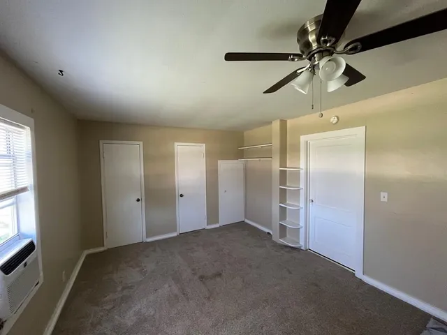 an empty room with a ceiling fan and a window