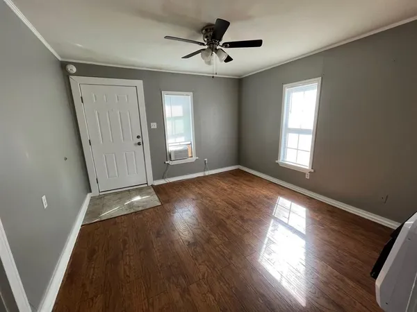 a view of an empty room with wooden floor and a window