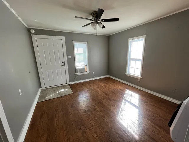 a view of an empty room with wooden floor and a window