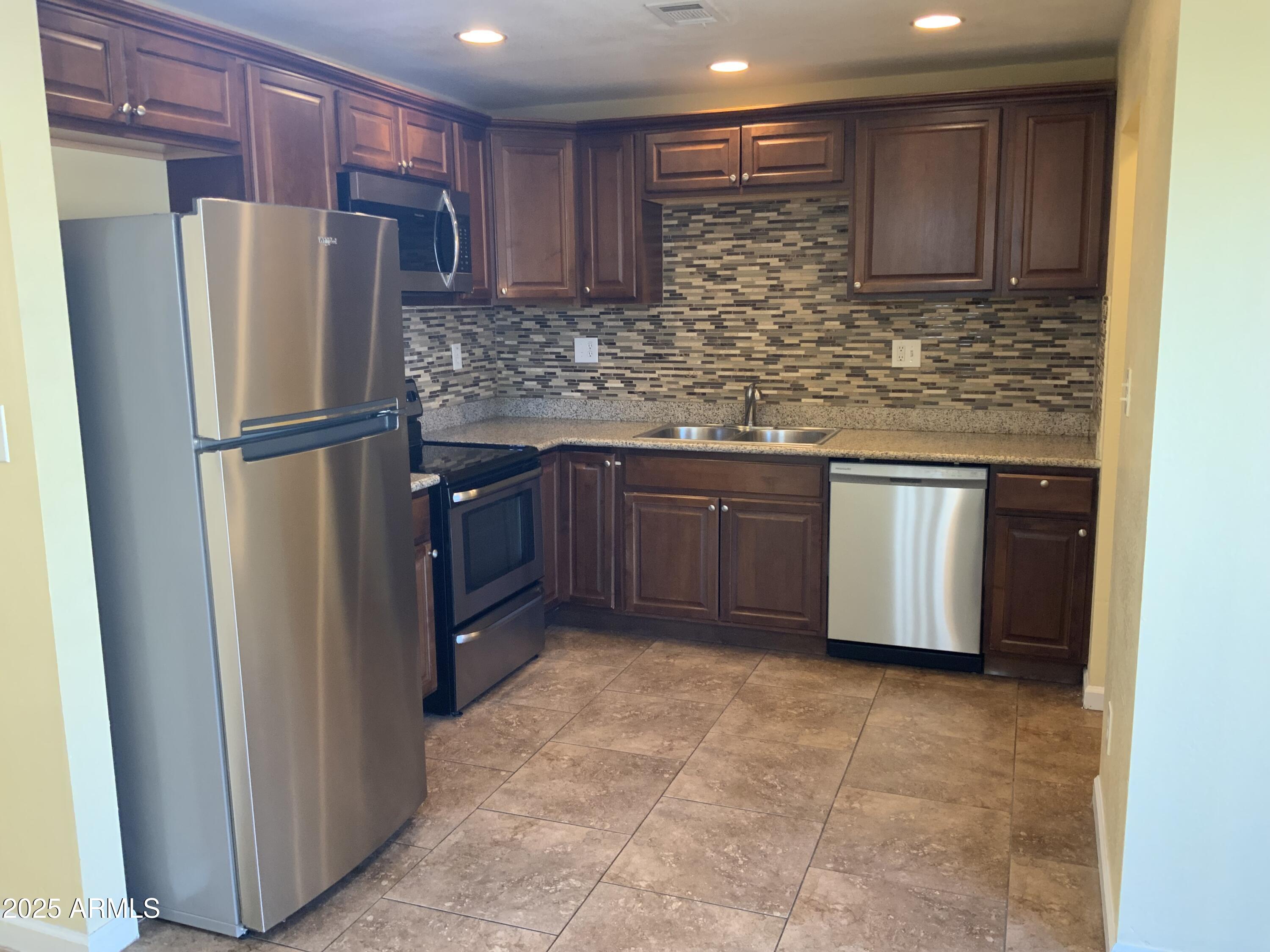 15831 North 59th Circle Glendale, AZ 85306 - Photo 3 of 12 a kitchen with stainless steel appliances granite countertop a refrigerator and a sink