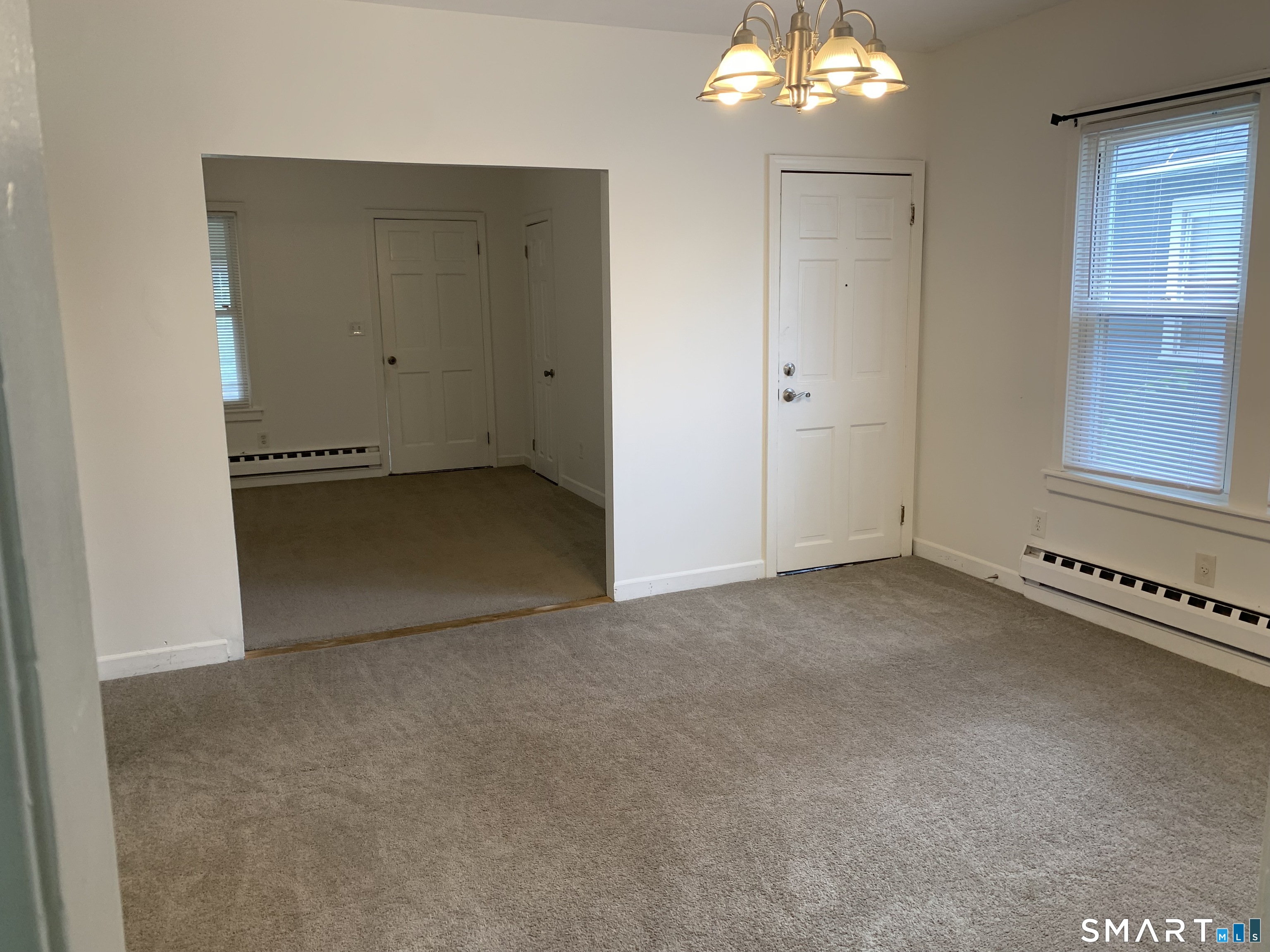112 Austin Street New Britain, CT 06051 - Photo 10 of 40 an empty room with a chandelier fan and windows