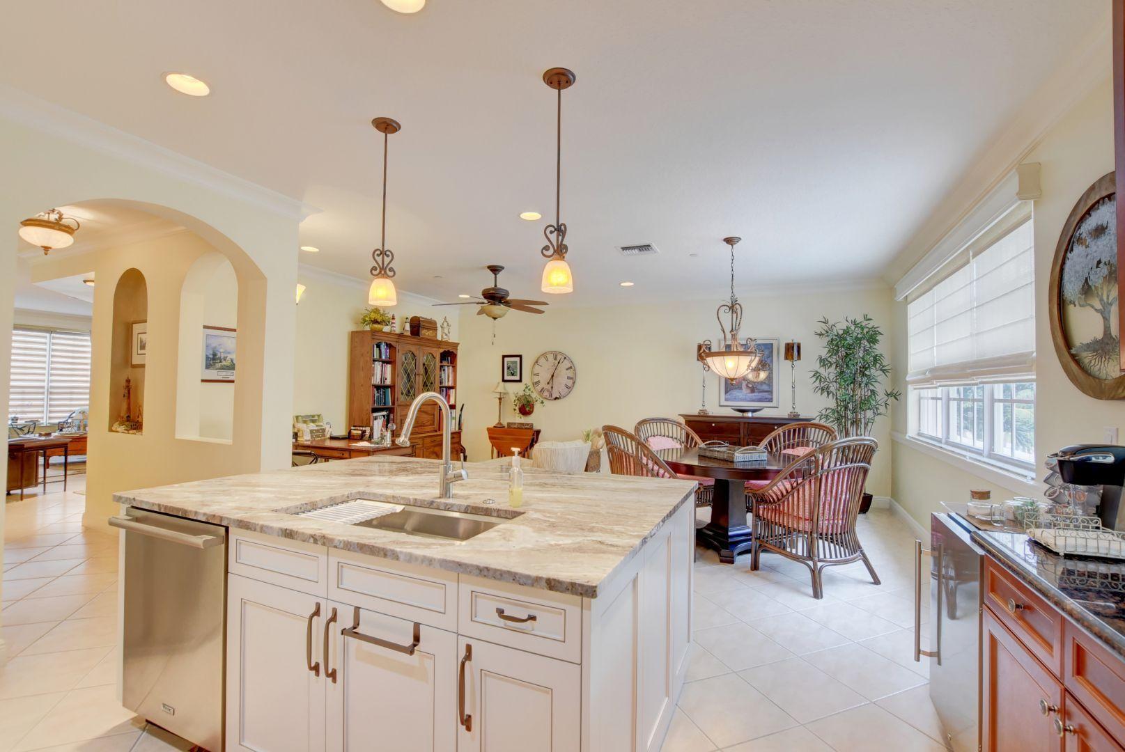 5530 Northeast Trieste Way Boca Raton, FL 33487 - Photo 1 of 56 a view of a kitchen with kitchen island granite countertop a stove a sink a dining table and chairs with wooden floor