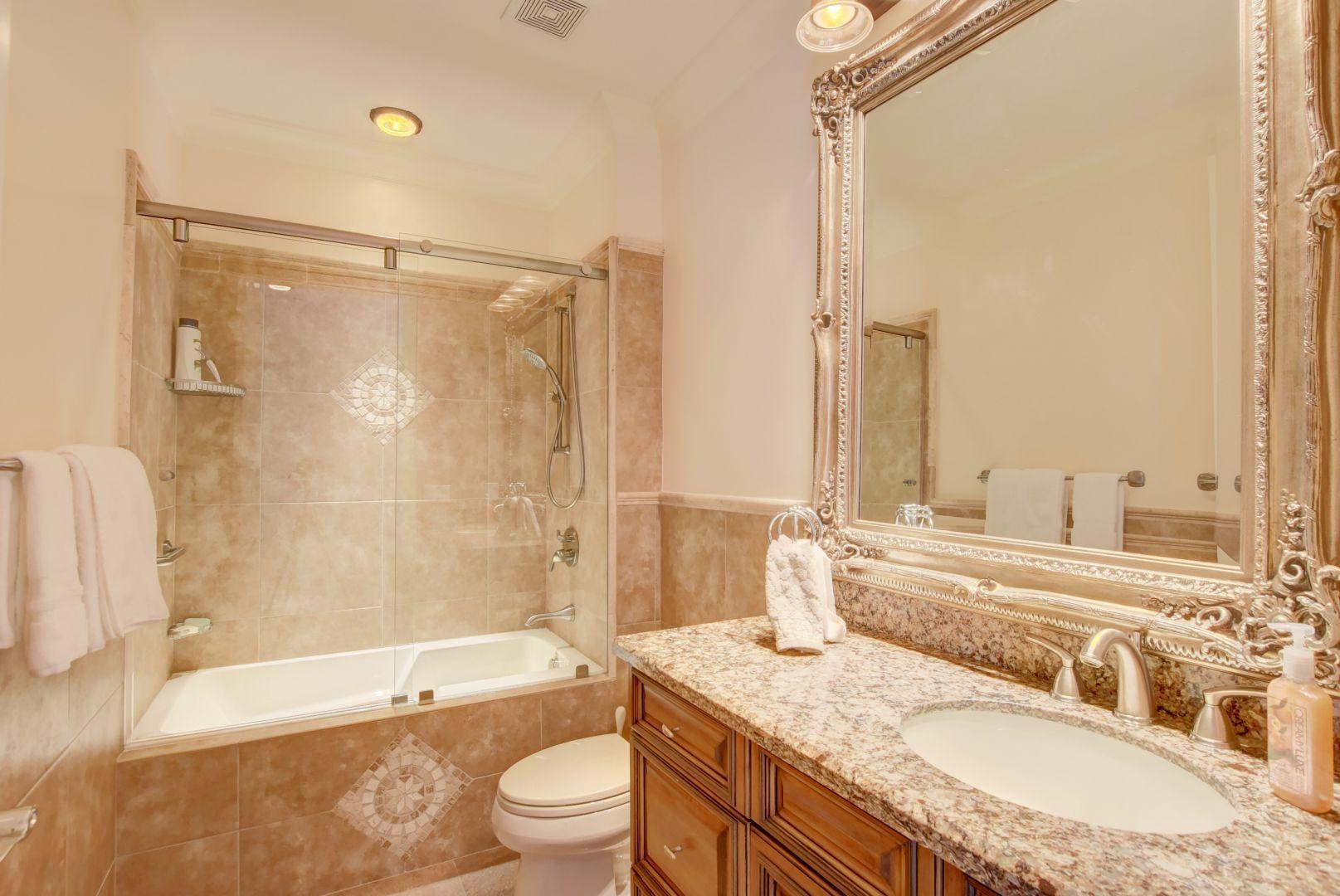 5530 Northeast Trieste Way Boca Raton, FL 33487 - Photo 25 of 56 a bathroom with a granite countertop bathtub shower sink vanity mirror and toilet