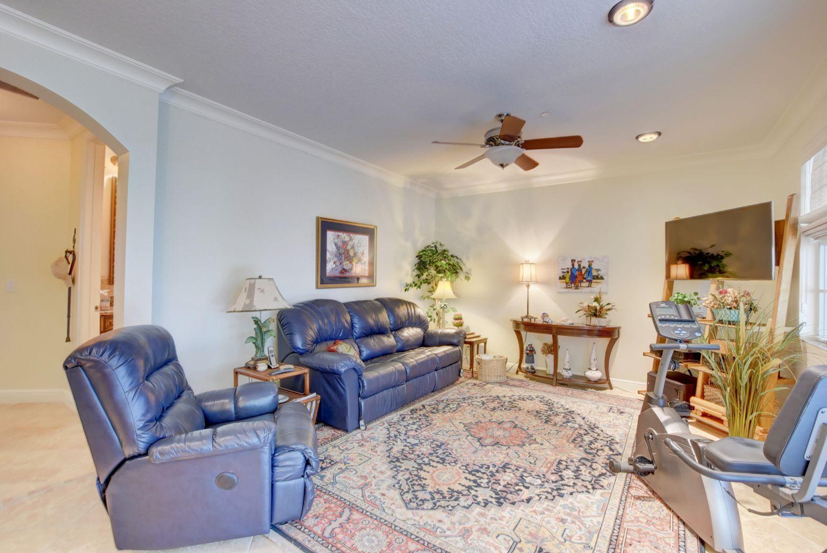 5530 Northeast Trieste Way Boca Raton, FL 33487 - Photo 29 of 56 a living room with furniture a ceiling fan and a flat screen tv