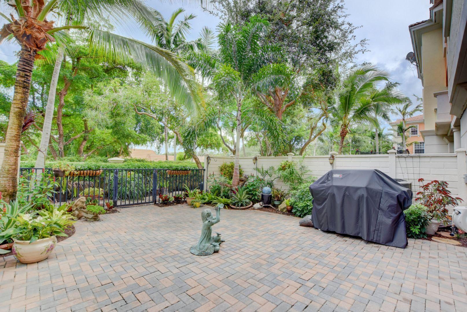 5530 Northeast Trieste Way Boca Raton, FL 33487 - Photo 38 of 56 a view of a garden with plants and a barbeque