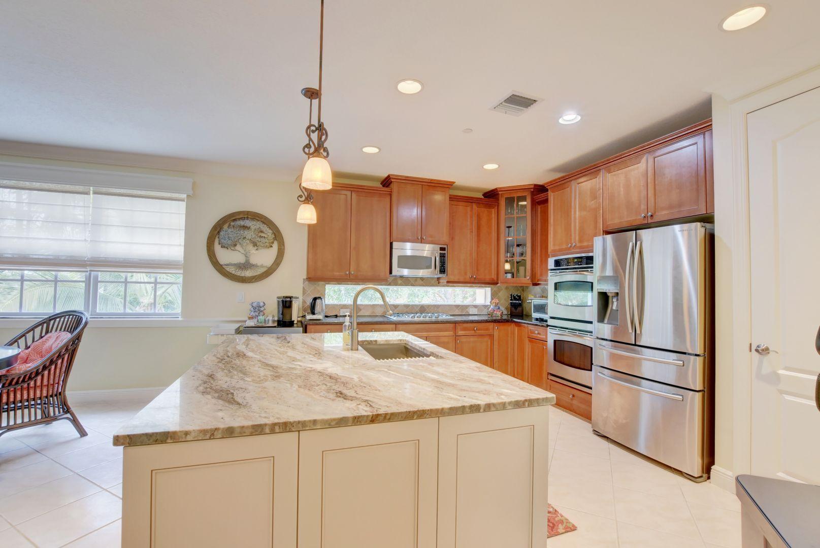 5530 Northeast Trieste Way Boca Raton, FL 33487 - Photo 4 of 56 a kitchen with granite countertop a refrigerator a stove a sink and a dining table with wooden floor