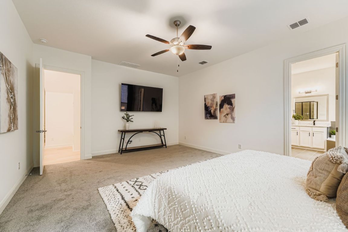 2928 Birdcall Path Leander, TX 78641 - Photo 17 of 36 a bedroom with a large bed and a flat screen tv