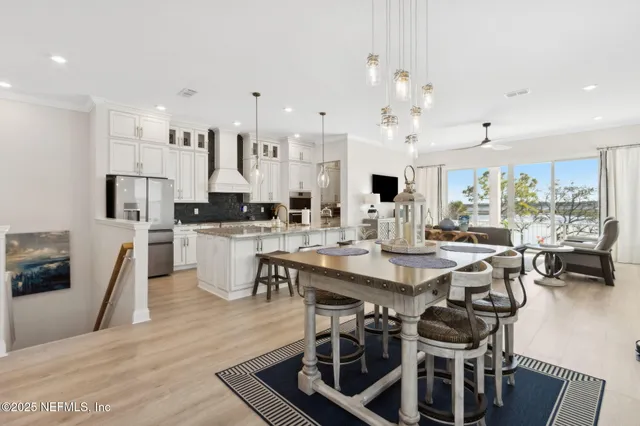 a kitchen with stainless steel appliances kitchen island granite countertop a table chairs and a white cabinets