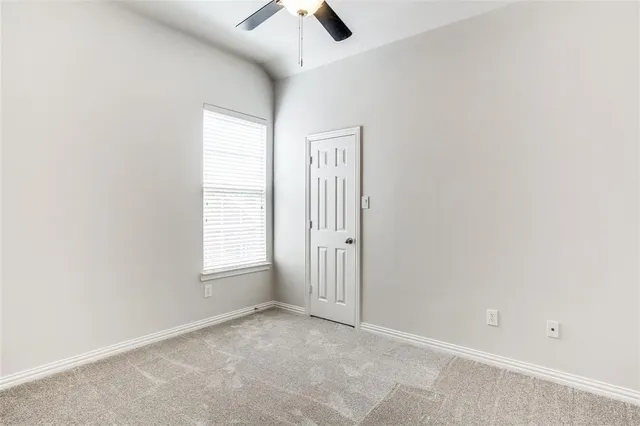 an empty room with windows and ceiling fan