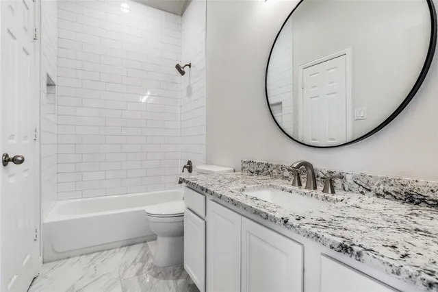 a bathroom with a granite countertop sink a toilet and a mirror