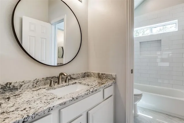 a bathroom with a granite countertop sink and a mirror