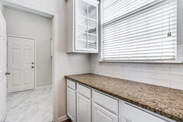 a kitchen with granite countertop white cabinets and a window