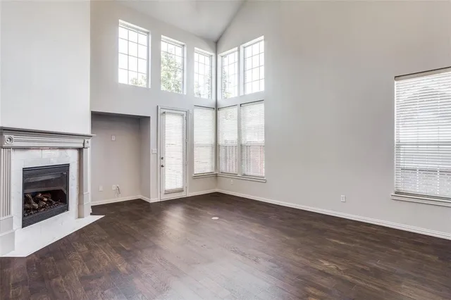 an empty room with wooden floor fireplace and windows
