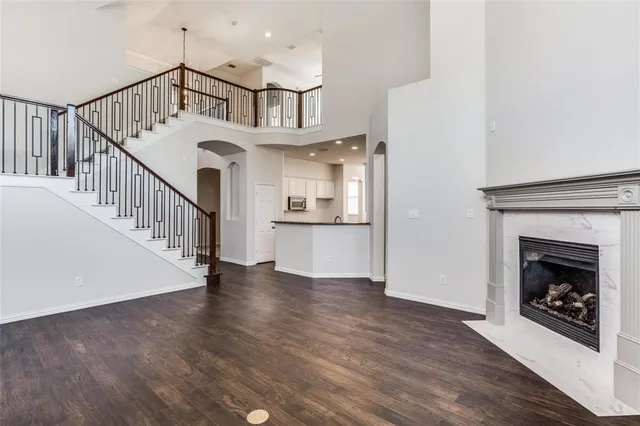 a view of an empty room with wooden floor fireplace and a window