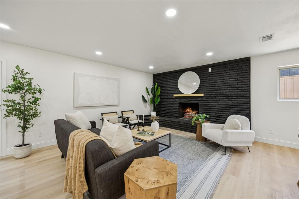 3115 Whirlaway Road Dallas, TX 75229 - Photo 9 of 28 Living area with a brick fireplace, recessed lighting, light wood-type flooring, and an accent wall