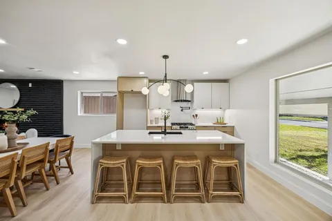 a kitchen with kitchen island a dining table and chairs