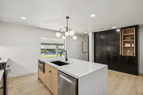 a kitchen with a sink a chandelier and wooden cabinets