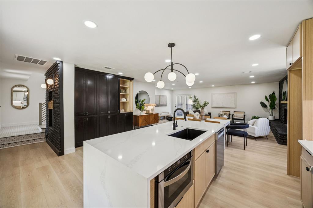 3115 Whirlaway Road Dallas, TX 75229 - Photo 28 of 28 Kitchen featuring a fireplace, open floor plan, light wood finished floors, a center island with sink, and recessed lighting