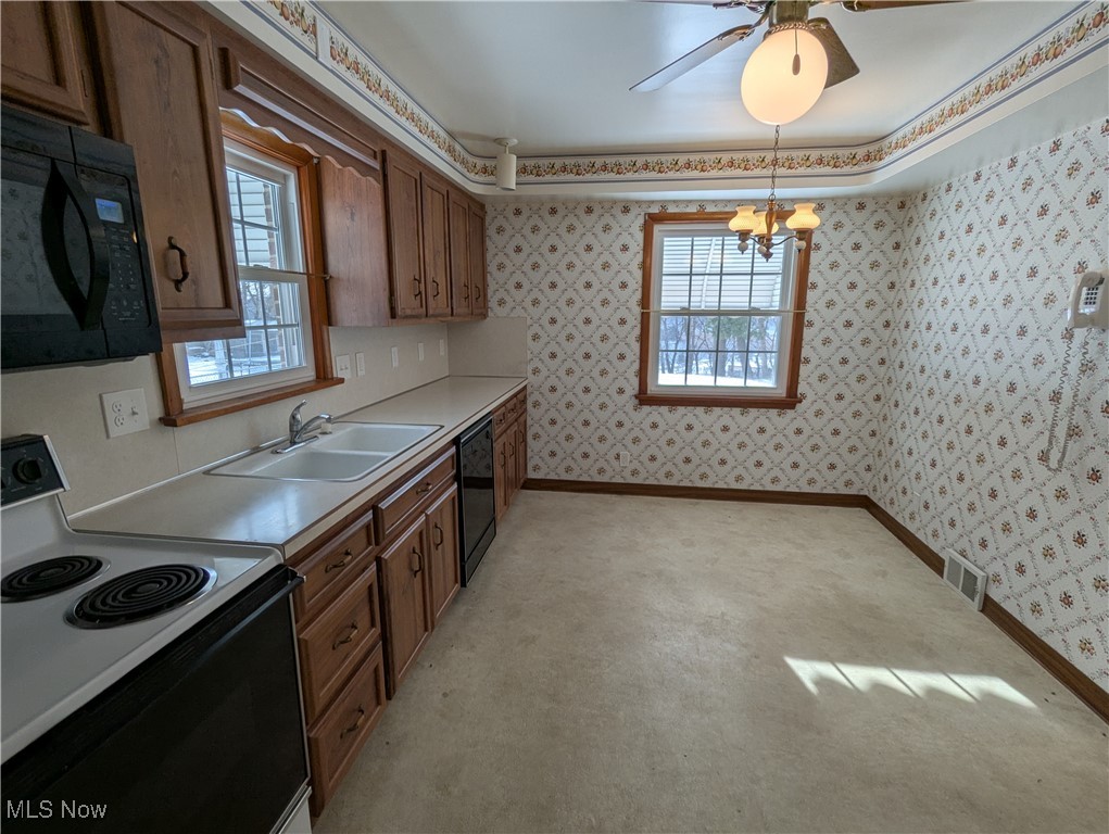 815 East Schaaf Road Independence, OH 44131 - Photo 11 of 36 Kitchen featuring pendant lighting, sink, an inviting chandelier, and black appliances