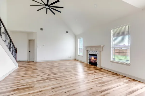 an empty room with windows fireplace and wooden floor