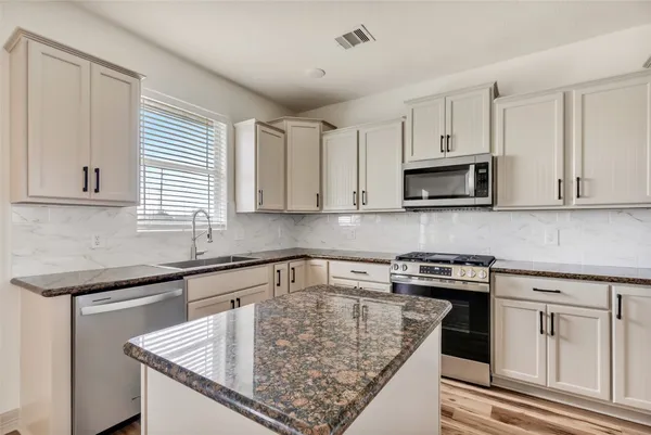 a kitchen with white cabinets sink and stove
