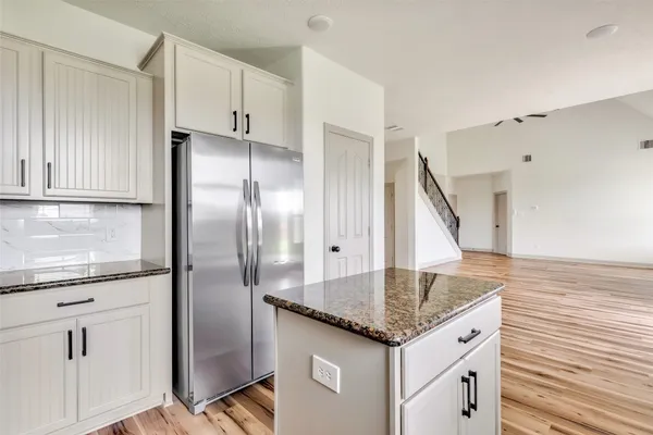 a kitchen with granite countertop a sink and refrigerator