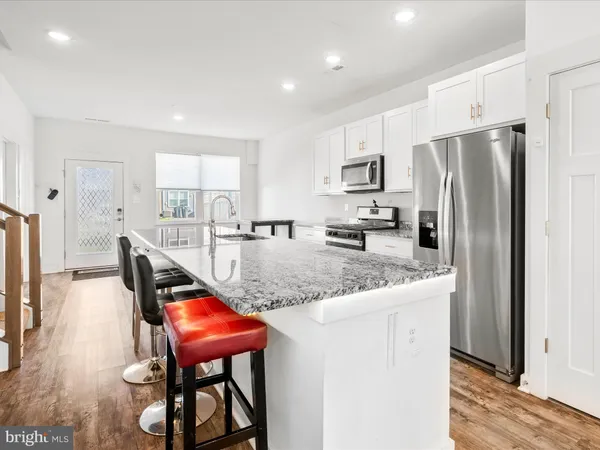 a kitchen with stainless steel appliances granite countertop a refrigerator a sink a stove a dining table and chairs