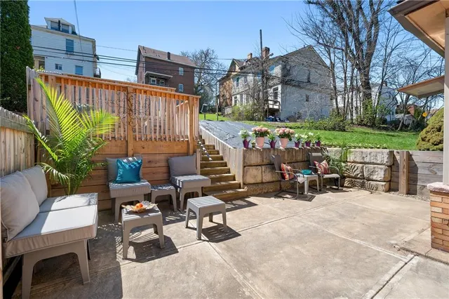 a view of a patio with couches table and chairs with wooden fence and plants