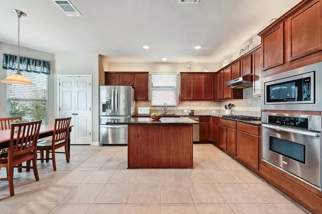 a kitchen with stainless steel appliances granite countertop a stove top oven a sink dishwasher a dining table and chairs