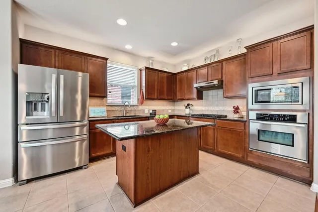 a kitchen with stainless steel appliances granite countertop a refrigerator stove top oven and sink