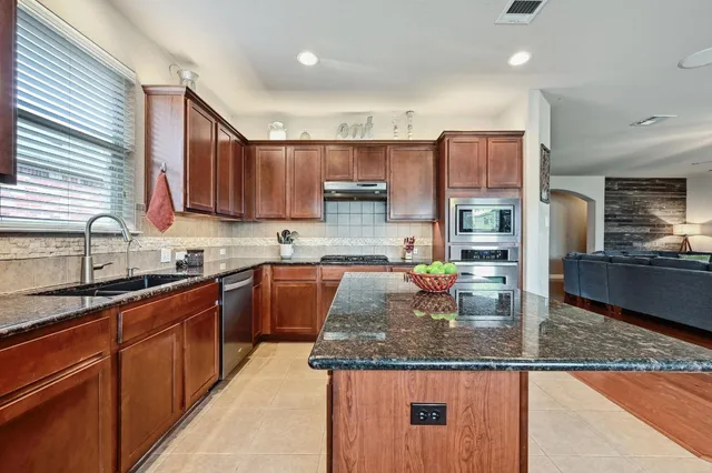 a kitchen with kitchen island granite countertop a sink counter top space appliances and cabinets
