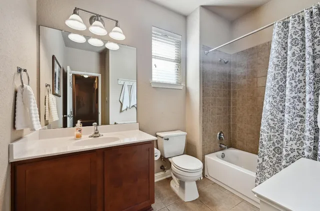 a bathroom with a sink a toilet a mirror a bathtub and shower