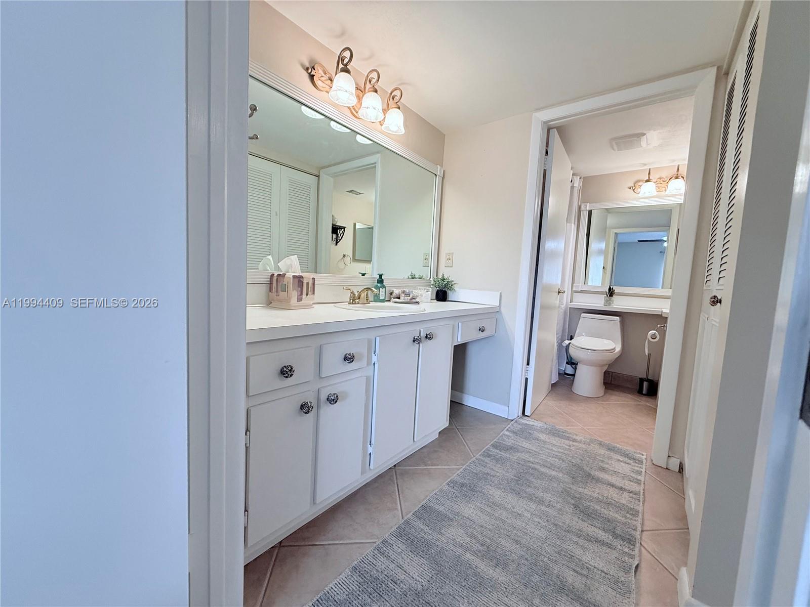 340 Pine Ridge Circle, Unit C1 Greenacres, FL 33463 - Photo 12 of 24 a en suite bathroom with a toilet sink and mirror
