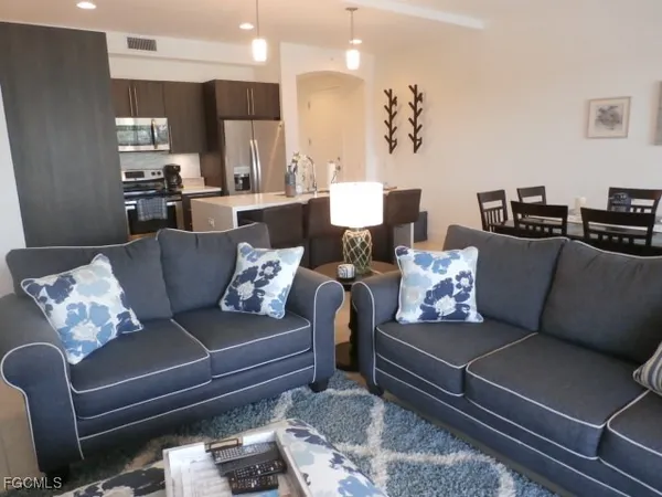 a living room with furniture kitchen view and a chandelier