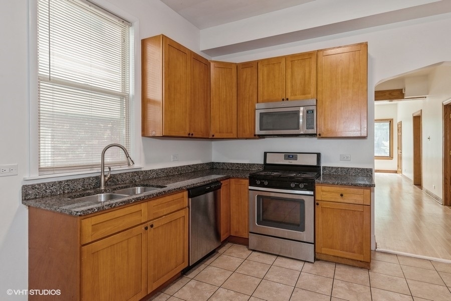 1840 West Huron Street, Unit 1 Chicago, IL 60622 - Photo 5 of 16 a kitchen with stainless steel appliances granite countertop a stove a sink and a microwave