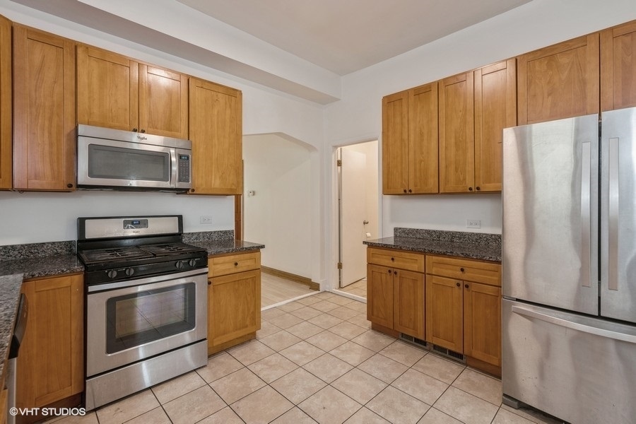 1840 West Huron Street, Unit 1 Chicago, IL 60622 - Photo 6 of 16 a kitchen with granite countertop a stove top oven microwave and refrigerator