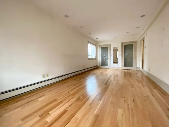 a view of a big room with wooden floor and windows